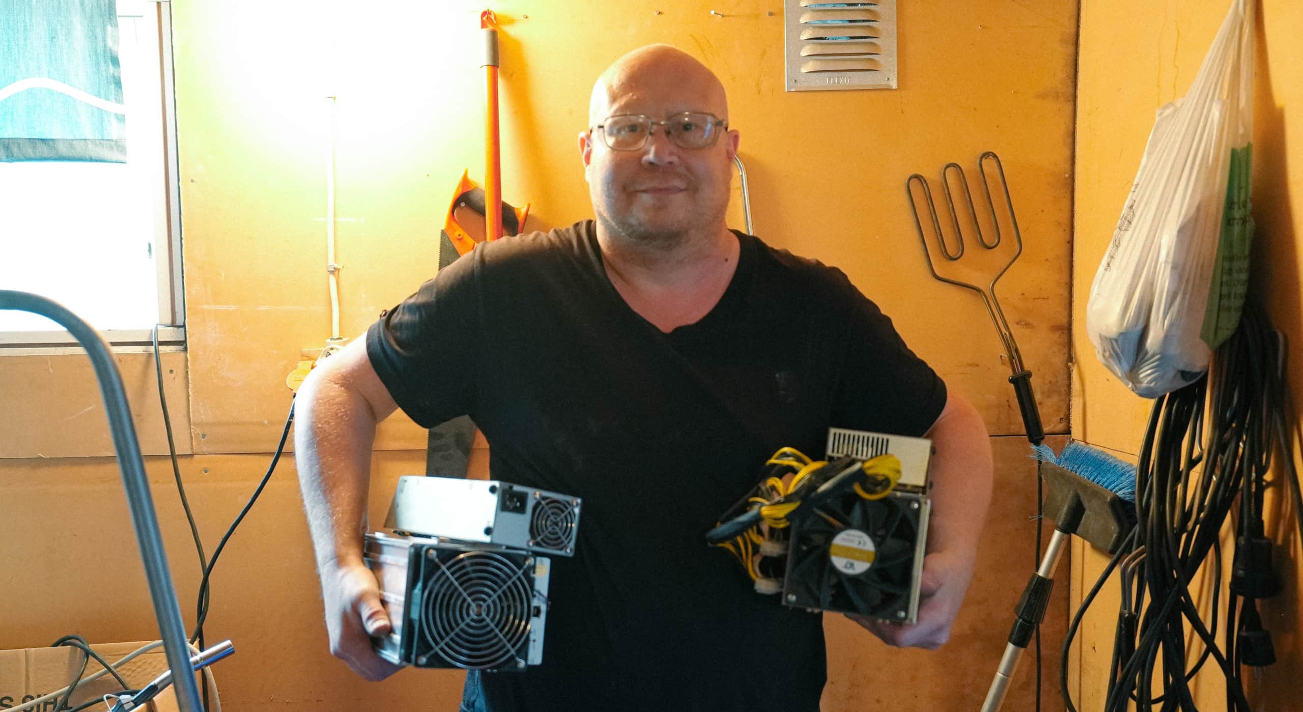 Man i ett garage som håller två maskiner i famnen