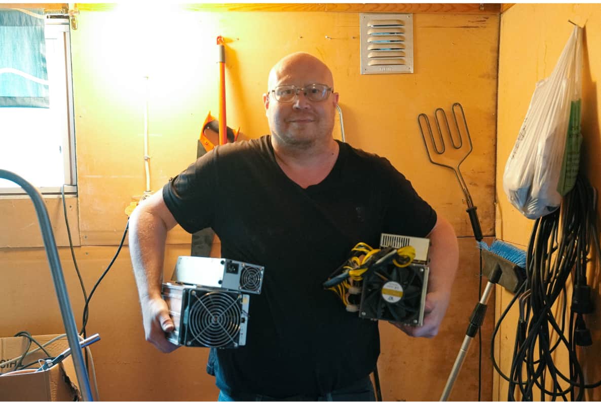 Mattias in his garage holding two bitcoin miners