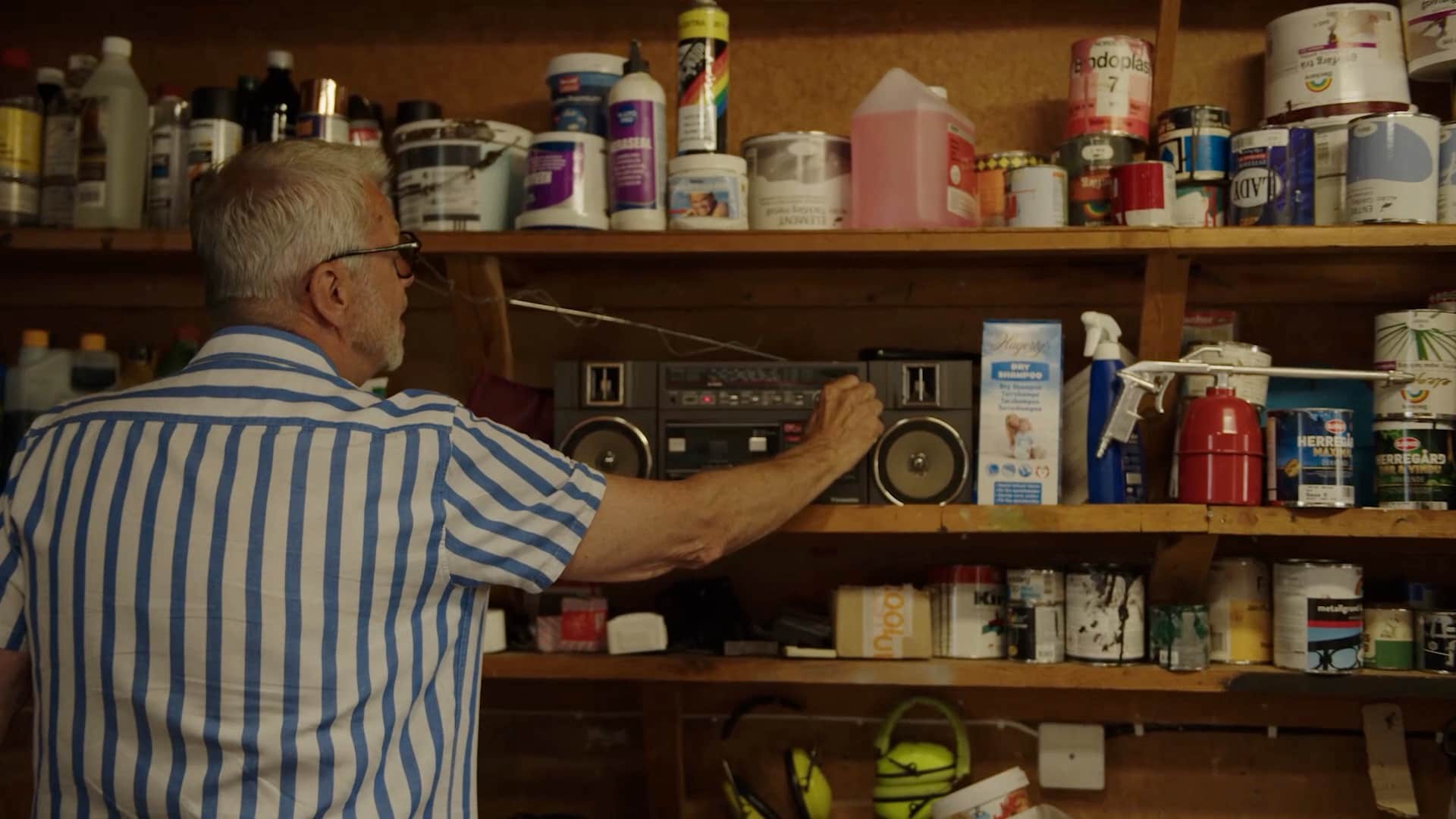 Older Elvy customer reaching for an old radio in a farm shed