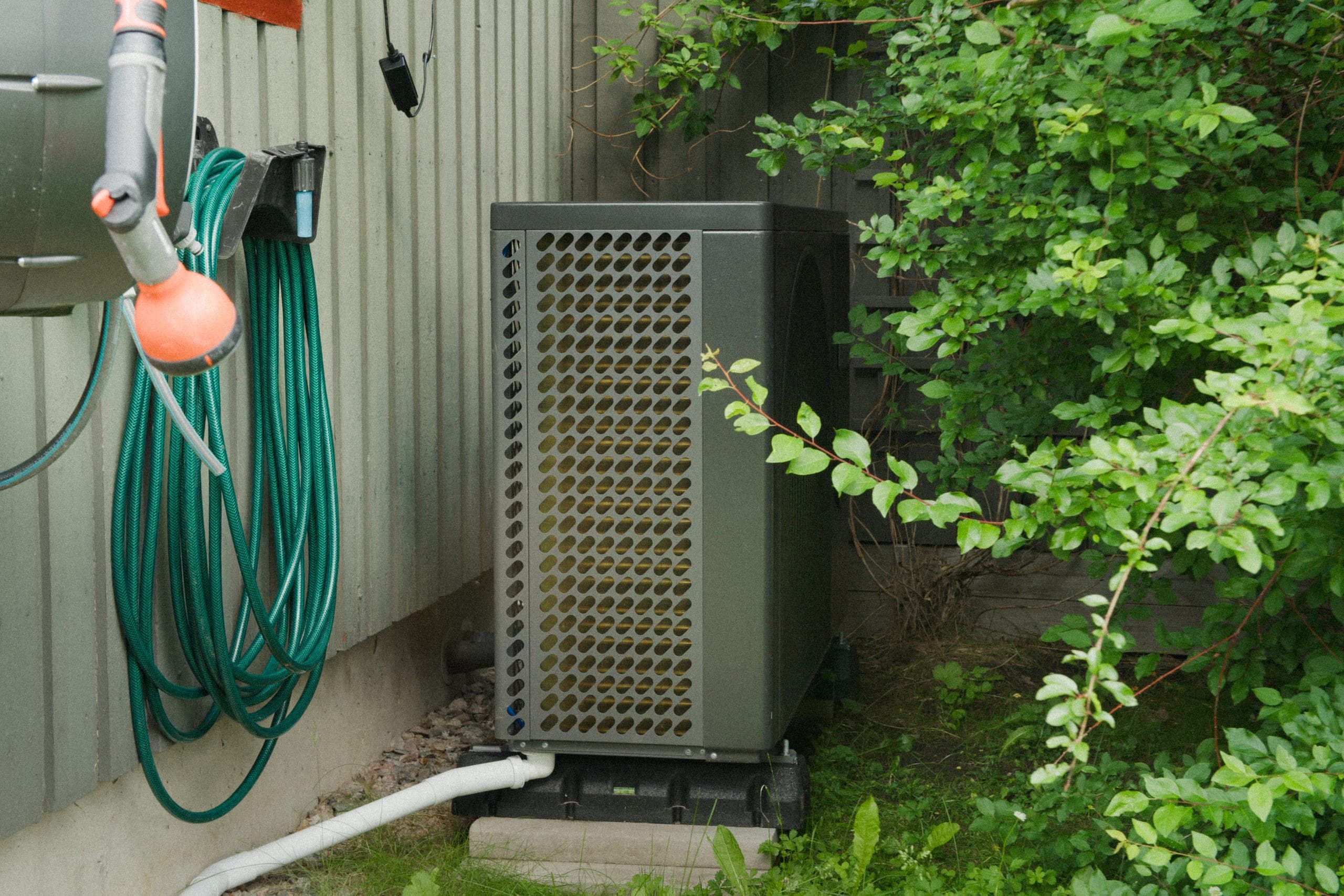 Utedelen till en luftvärmepump på ett fundament vid husväggen
