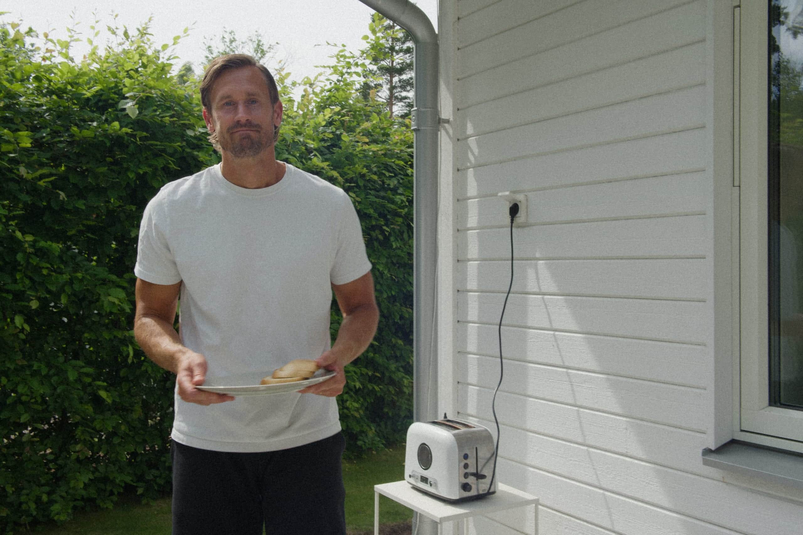 Elvy-kund med en tallrik rostat bröd utanför sitt hus