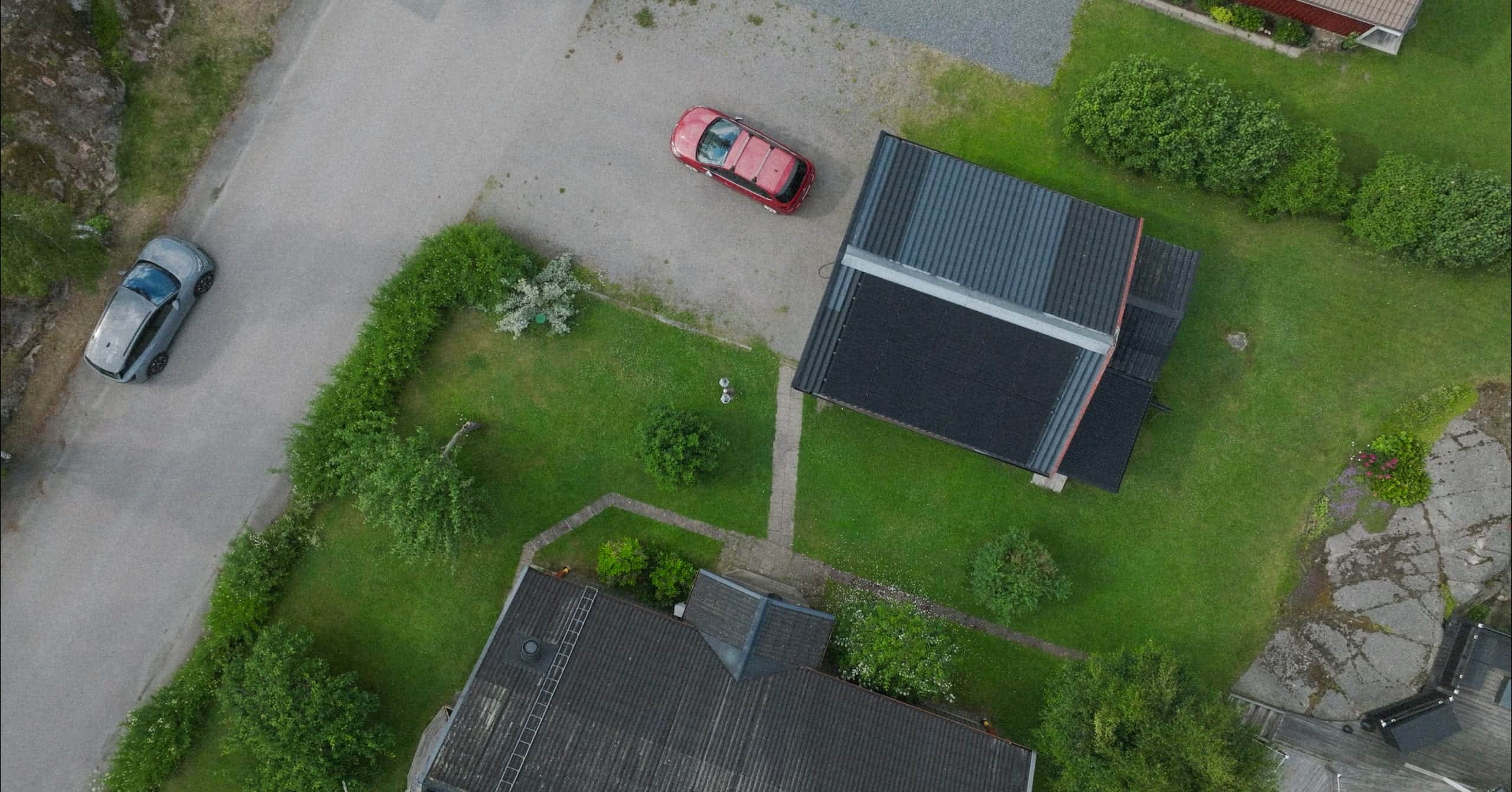 Aerial view of a villa with solar panels and a driveway in a residential area